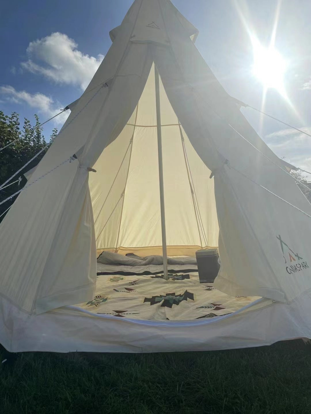 White tent with a patterned interior on grass under a blue sky
